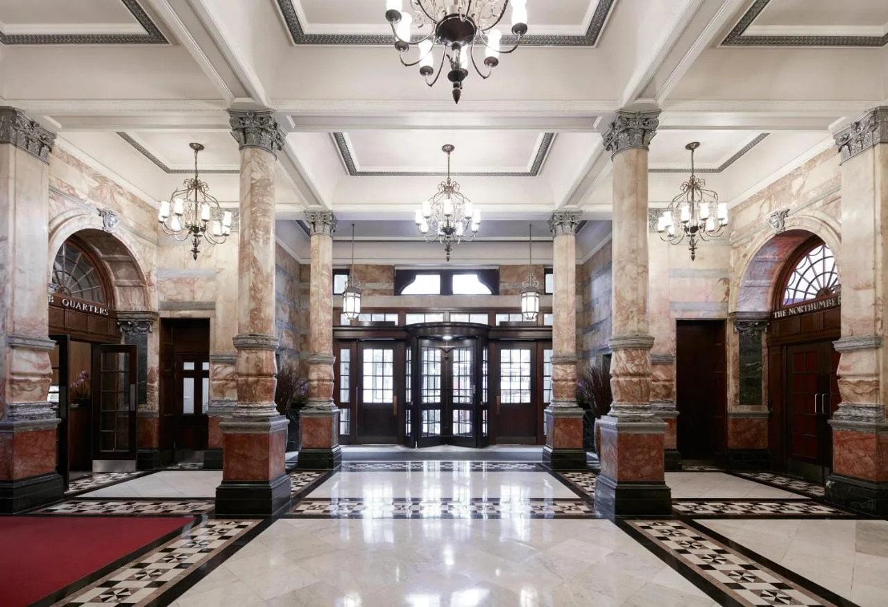 an ornate lobby with a chandelier and columns at The Grand at Trafalgar Square in London