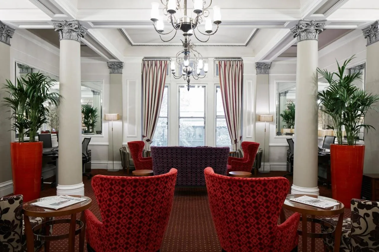 a dining room with red chairs and a chandelier at The Grand at Trafalgar Square in London
