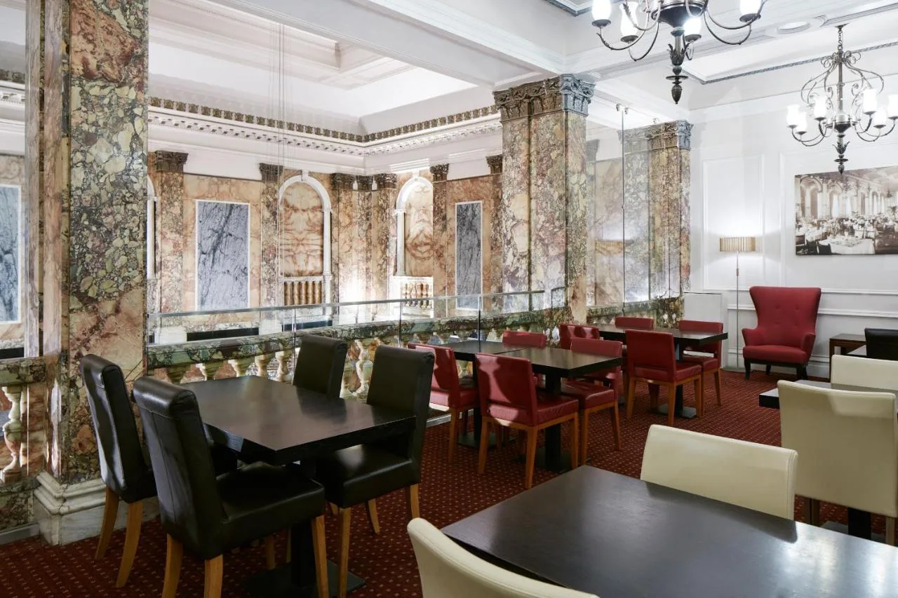 a dining room with tables and chairs and paintings on the walls at The Grand at Trafalgar Square in London