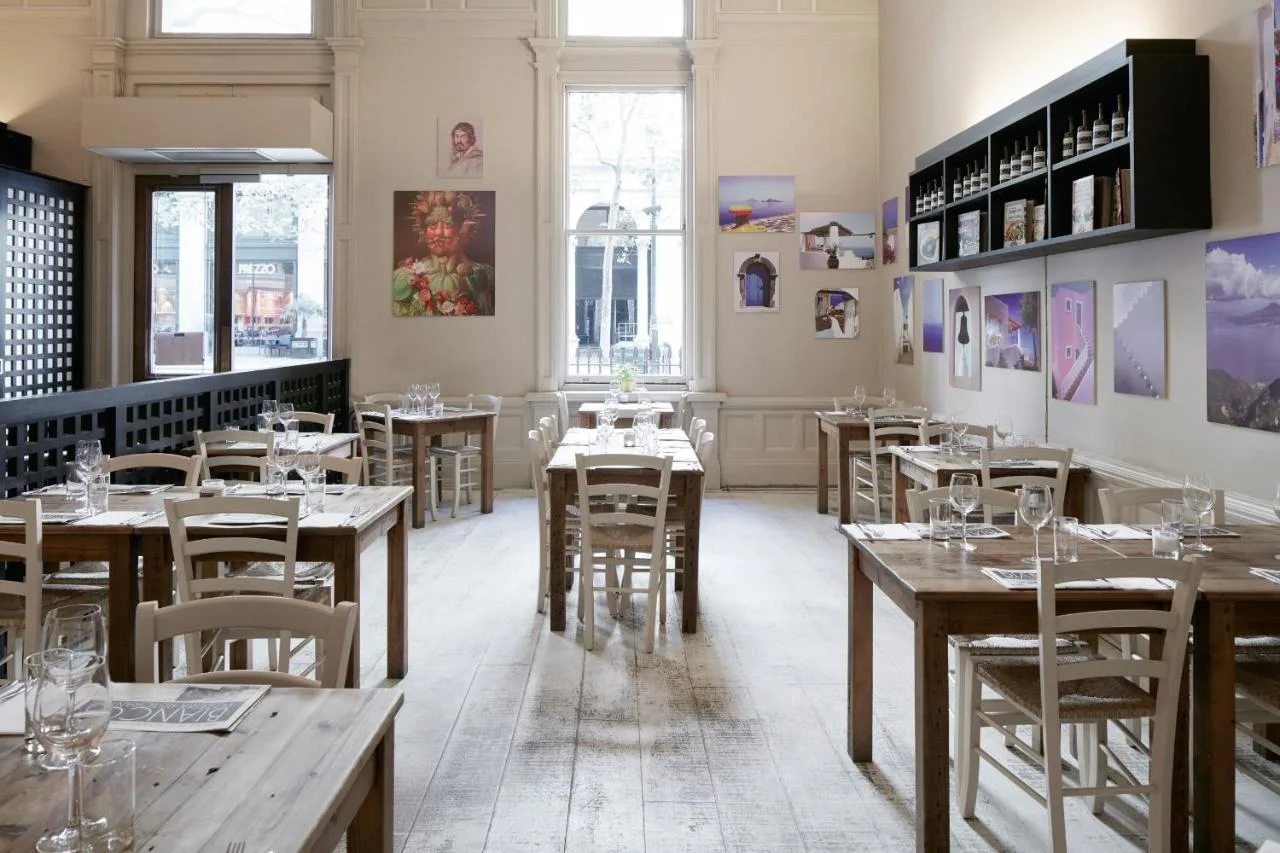 a restaurant with wooden tables and chairs in a room at The Grand at Trafalgar Square in London